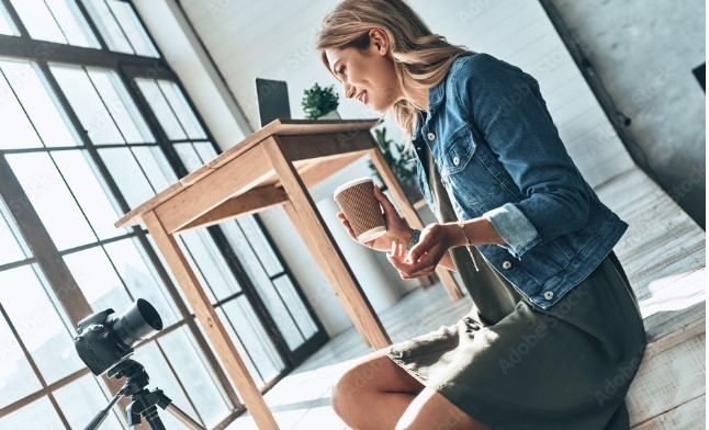 Influencerin filmt sich mit dem Smartphone an einem Tisch