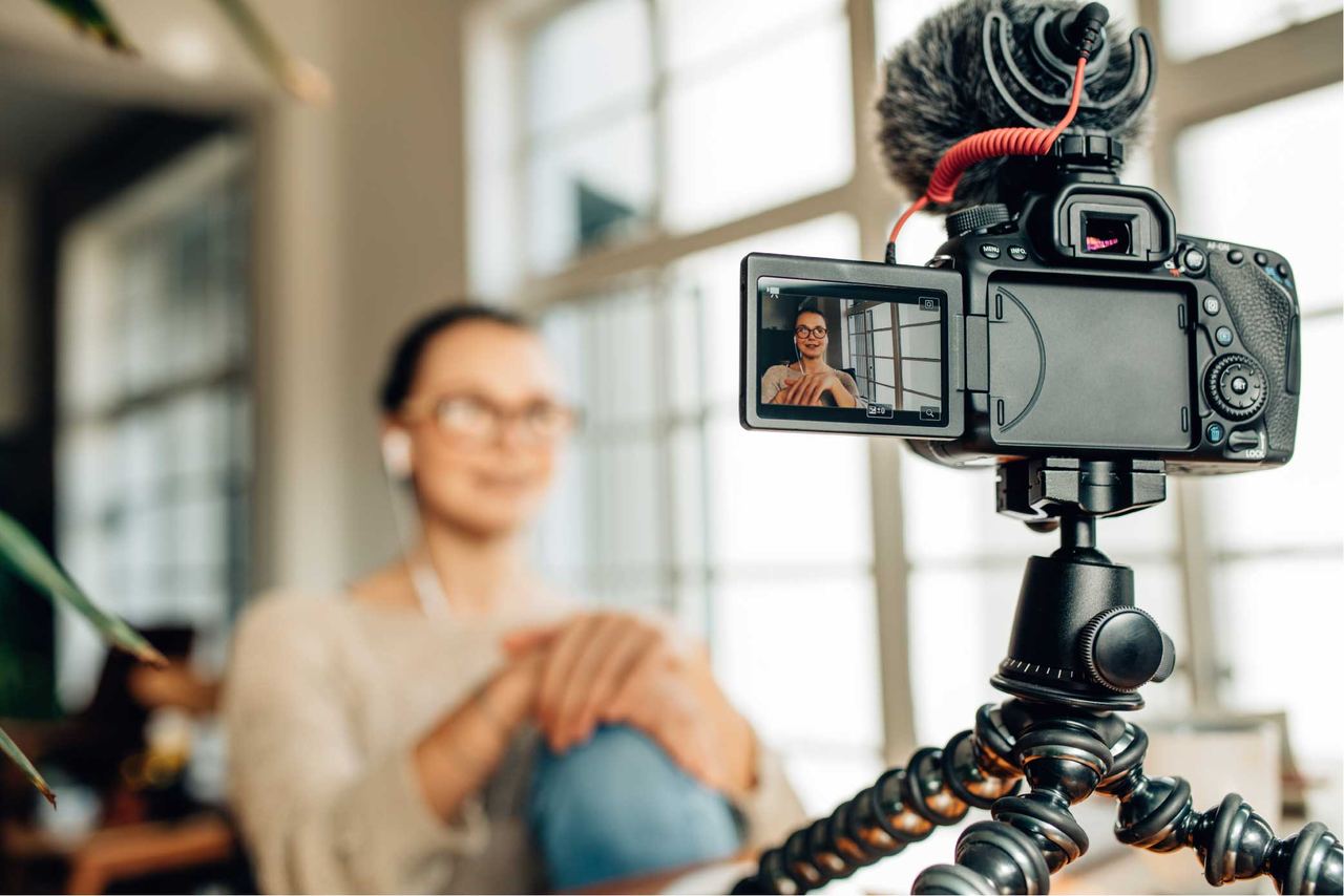 Frau vor einer Kamera mit Mikrofon auf dem Stativ bei einer Videoproduktion